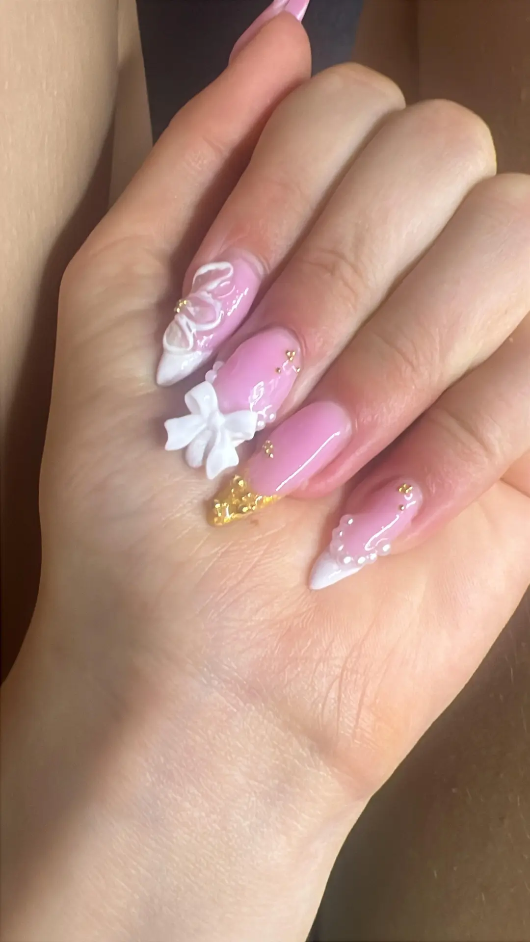 Rosa naglar med guldrosetter och vita 3D-blommor