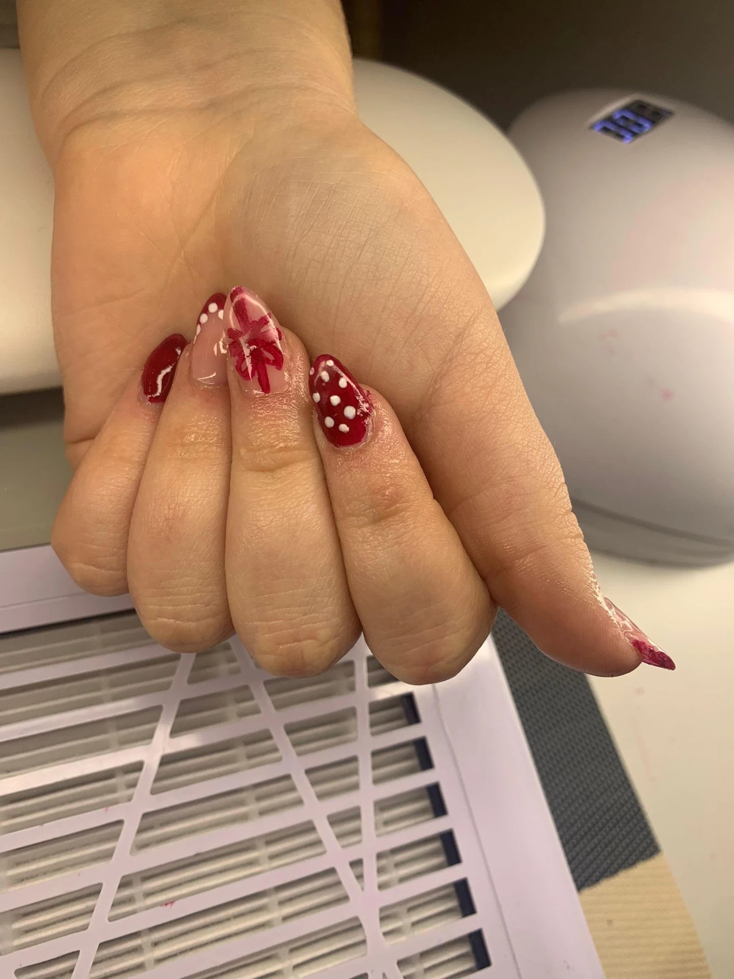 Röda naglar med handmålad rosett och vita prickar